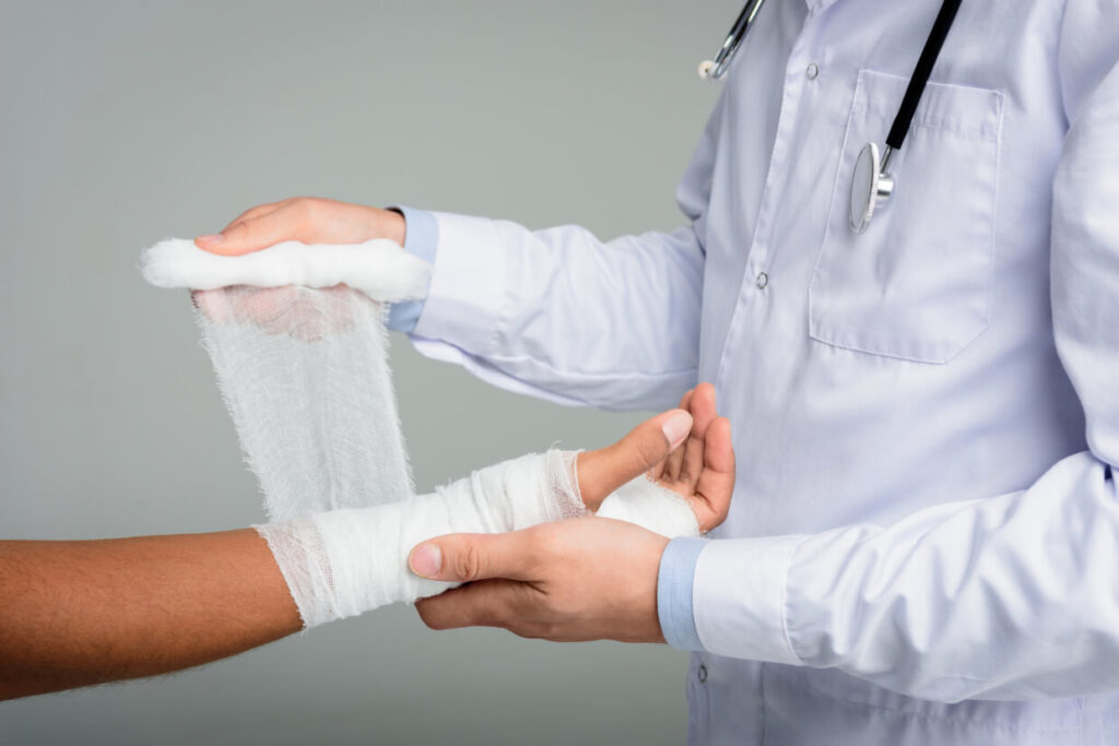 Doctor bandaging patient's arm wound with medical gauze