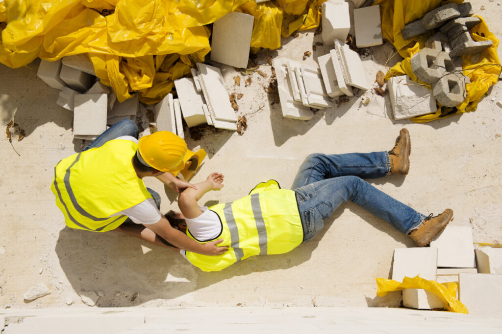 Construction workers in safety gear lying on concrete ground