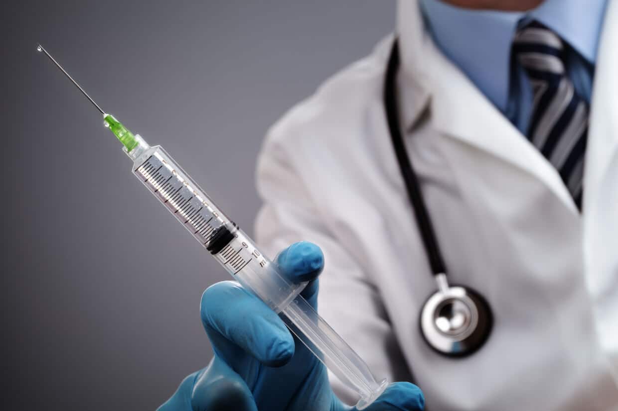 Abbey Court Solicitors | Needle Stick InjuryDoctor in white coat holding medical syringe with green liquid Doctor in white coat holding medical syringe with green liquid