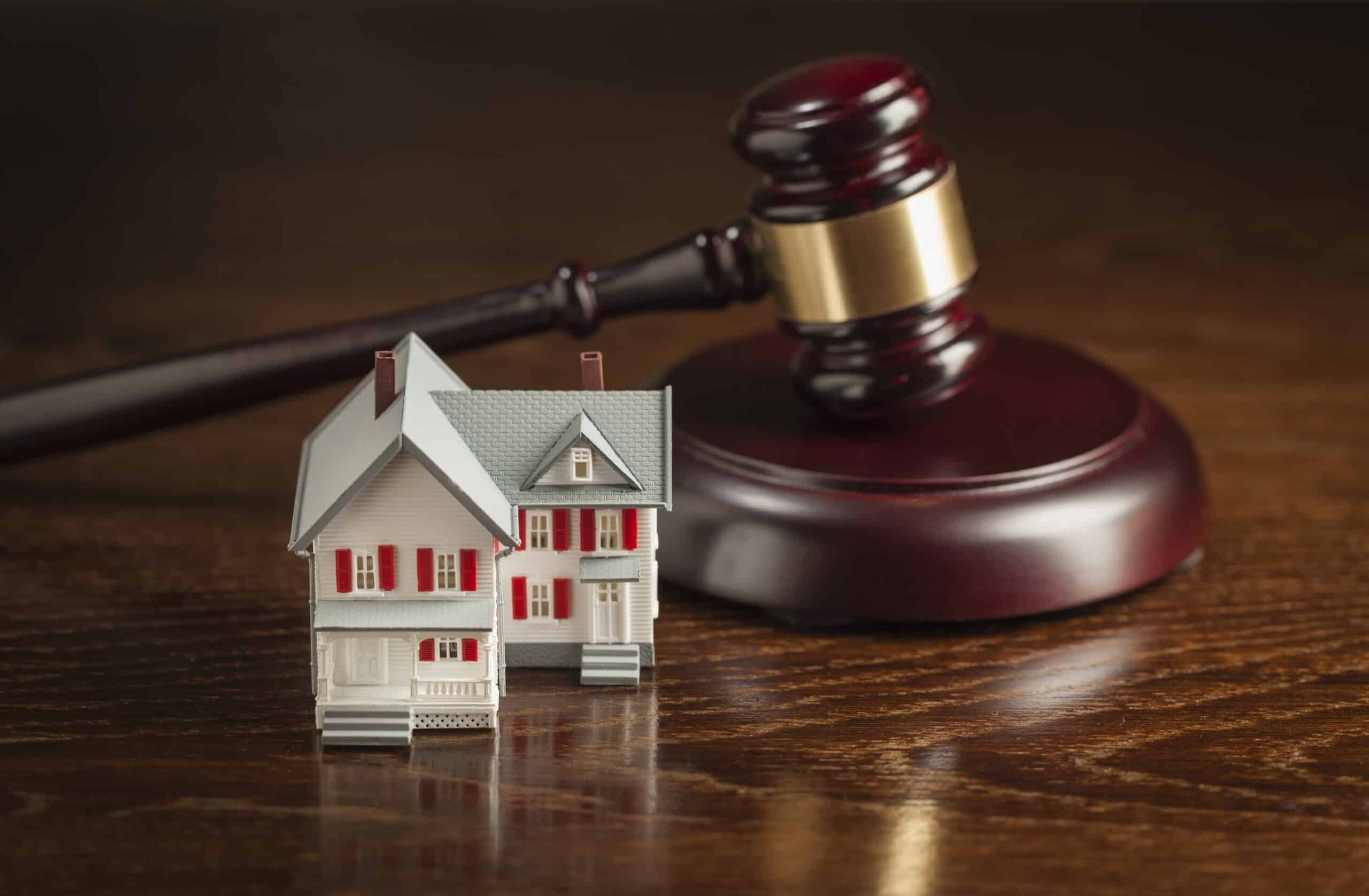 Gavel and Small Model House on Wooden Table. Miniature house model with judge's gavel on wooden surface