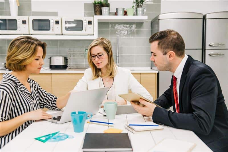 456978 Three professionals collaborating in modern kitchen office space