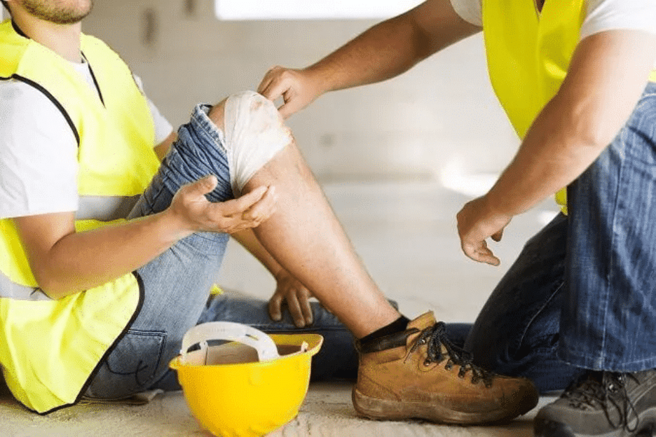 Construction worker bandaging injured leg at workplace